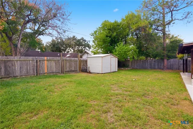 a view of a backyard with large trees and wooden fence