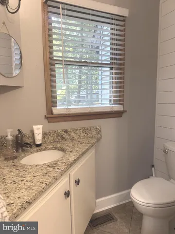 a bathroom with a granite countertop sink and a toilet