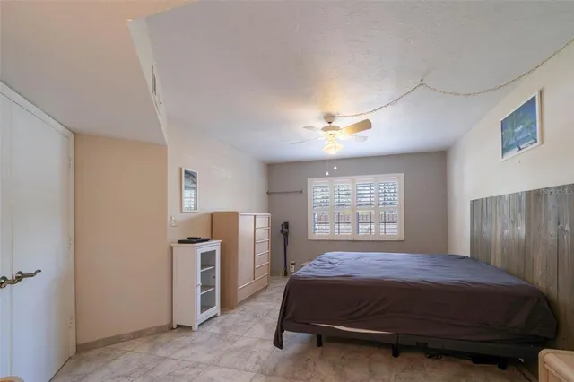 a bed sitting in a spacious bedroom next to a window and a chandelier