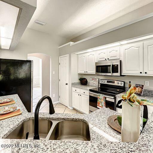 2950 Lakeside Villa Road Orange Park, FL 32073 - Photo 24 of 44 a kitchen with stainless steel appliances kitchen island granite countertop a stove top oven a sink dishwasher and white cabinets with wooden floor