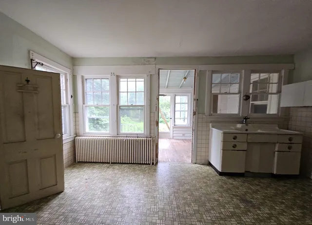 a room with kitchen island stainless steel appliances a stove a sink and a large window