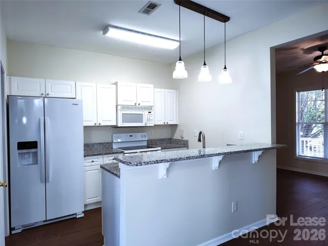 a kitchen with stainless steel appliances a sink a stove a refrigerator a center island with wooden floor