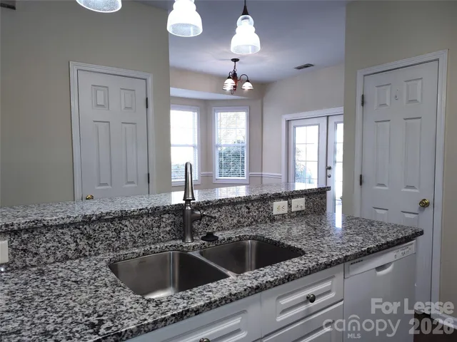 a kitchen with a granite countertop sink a window and chandelier