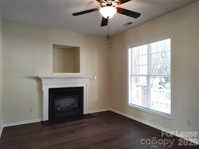 a view of an empty room with wooden floor and a fireplace