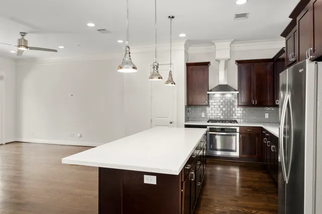a kitchen with stainless steel appliances kitchen island granite countertop a stove top oven a sink a dining table and chairs with wooden floor