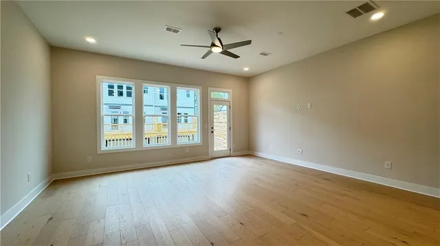 a view of an empty room with a window and wooden floor