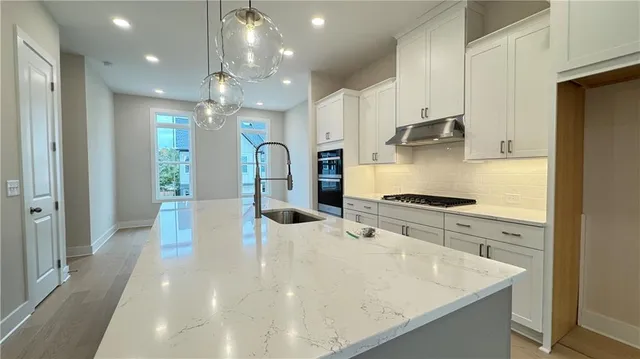 a kitchen with stainless steel appliances granite countertop a sink a stove and a refrigerator