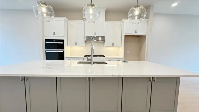 a kitchen with stainless steel appliances a kitchen island hardwood floor sink stove and cabinets