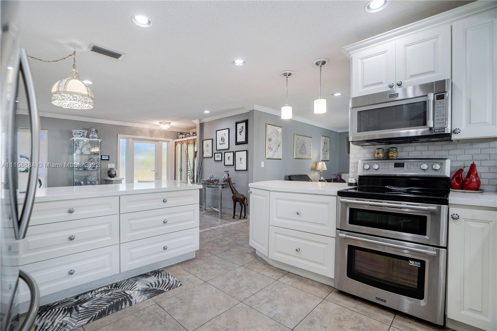 5012 Hayes Street Hollywood, FL 33021 - Photo 11 of 36 a kitchen with stainless steel appliances a stove microwave and cabinets