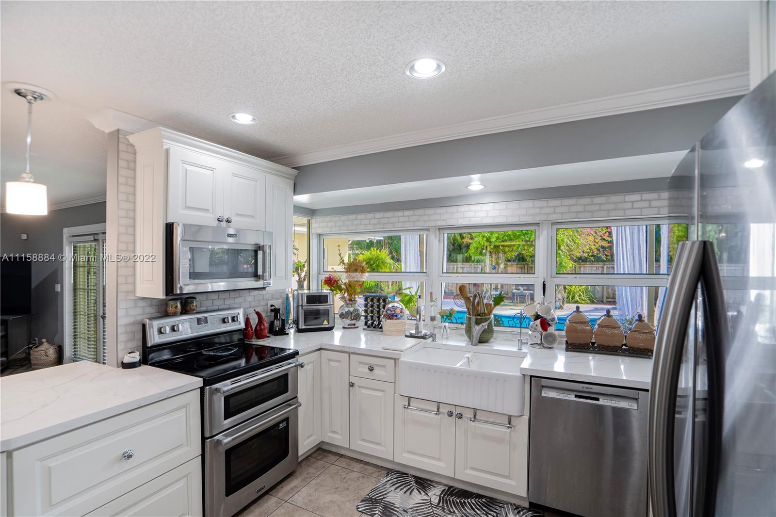 5012 Hayes Street Hollywood, FL 33021 - Photo 9 of 36 a kitchen with stainless steel appliances granite countertop a stove a sink and a refrigerator