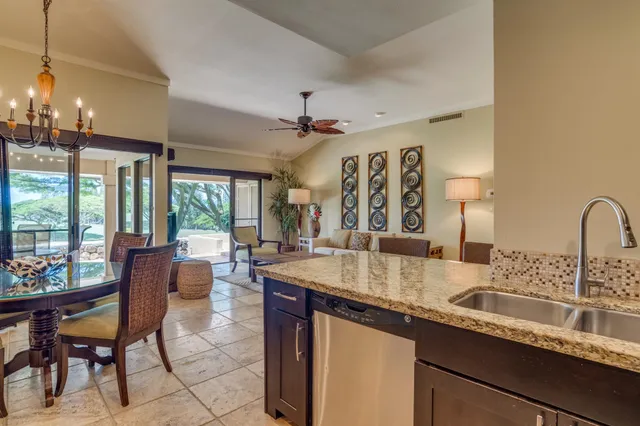 a kitchen with granite countertop a sink and a dining table with chairs