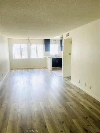 an empty room with wooden floor cabinet and windows