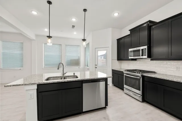 a kitchen with stainless steel appliances granite countertop a sink a stove a refrigerator and a microwave