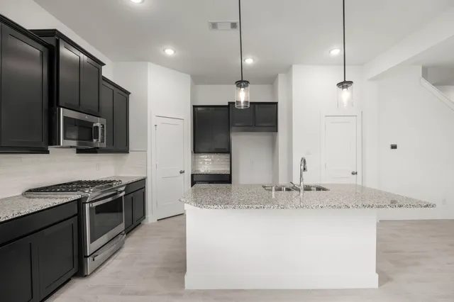 a kitchen with kitchen island granite countertop a sink and stainless steel appliances