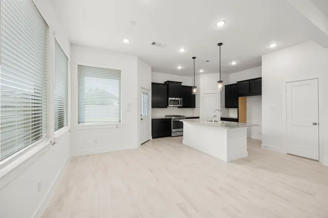 a view of kitchen with kitchen island granite countertop a stove top oven a sink and dishwasher with wooden floor