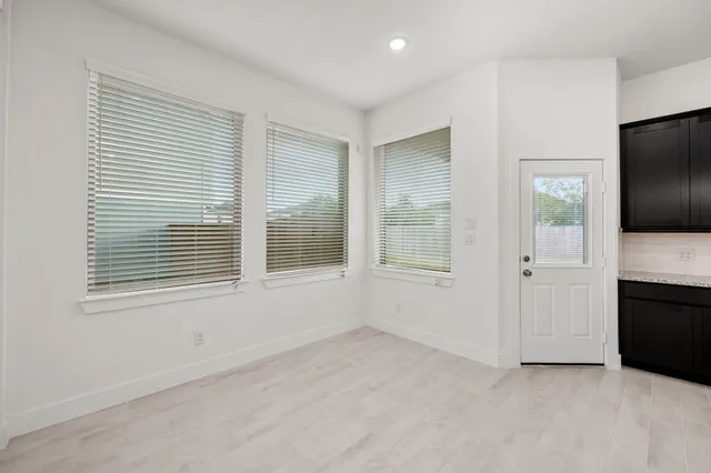 a view of an empty room with a window and a kitchen