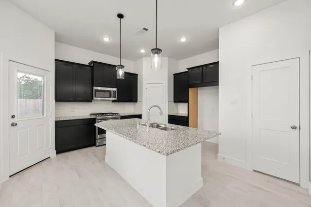 a kitchen with stainless steel appliances granite countertop a sink a microwave a refrigerator and a stove top oven