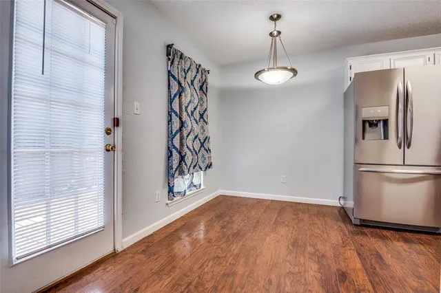 an empty room with wooden floor fireplace and windows