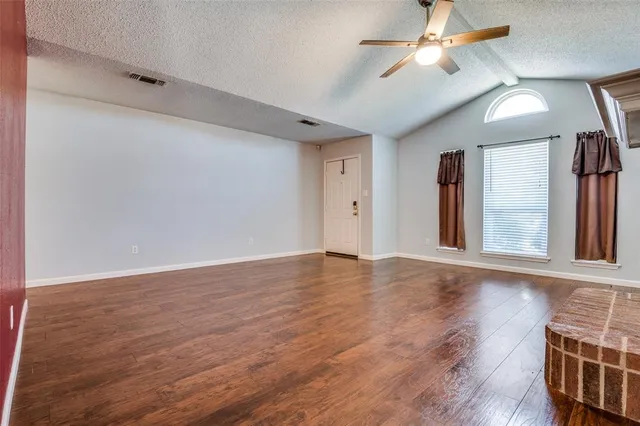 a view of a livingroom with wooden floor a ceiling fan and a fireplace