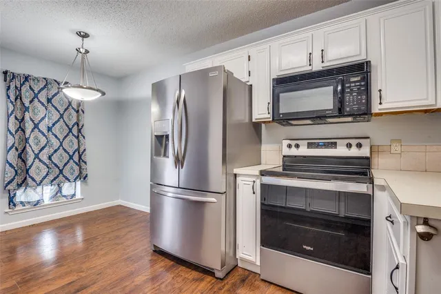 a kitchen with stainless steel appliances a sink dishwasher a stove and white cabinets with wooden floor