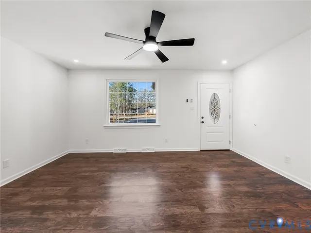 a view of empty room with wooden floor and ceiling fan