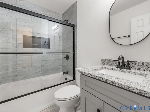 a bathroom with a granite countertop sink a toilet and shower