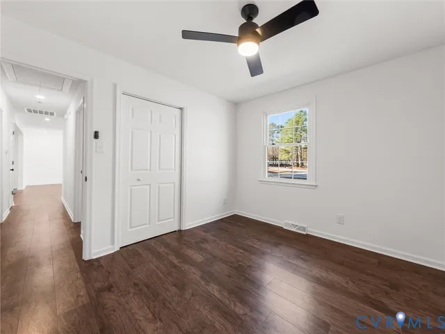 an empty room with wooden floor ceiling fan and windows