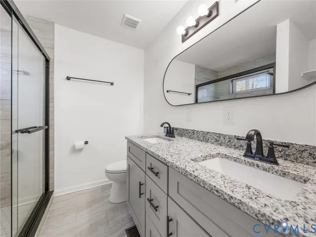 a bathroom with a granite countertop sink a toilet and a mirror
