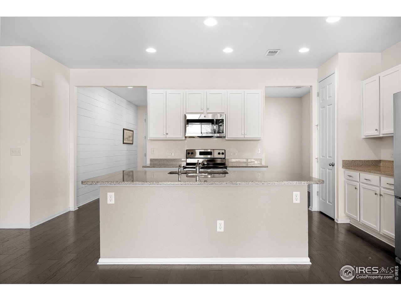 1604 Sorenson Drive Windsor, CO 80550 - Photo 7 of 32 a kitchen with stainless steel appliances granite countertop a sink a stove a refrigerator a microwave oven with white cabinets and wooden floor