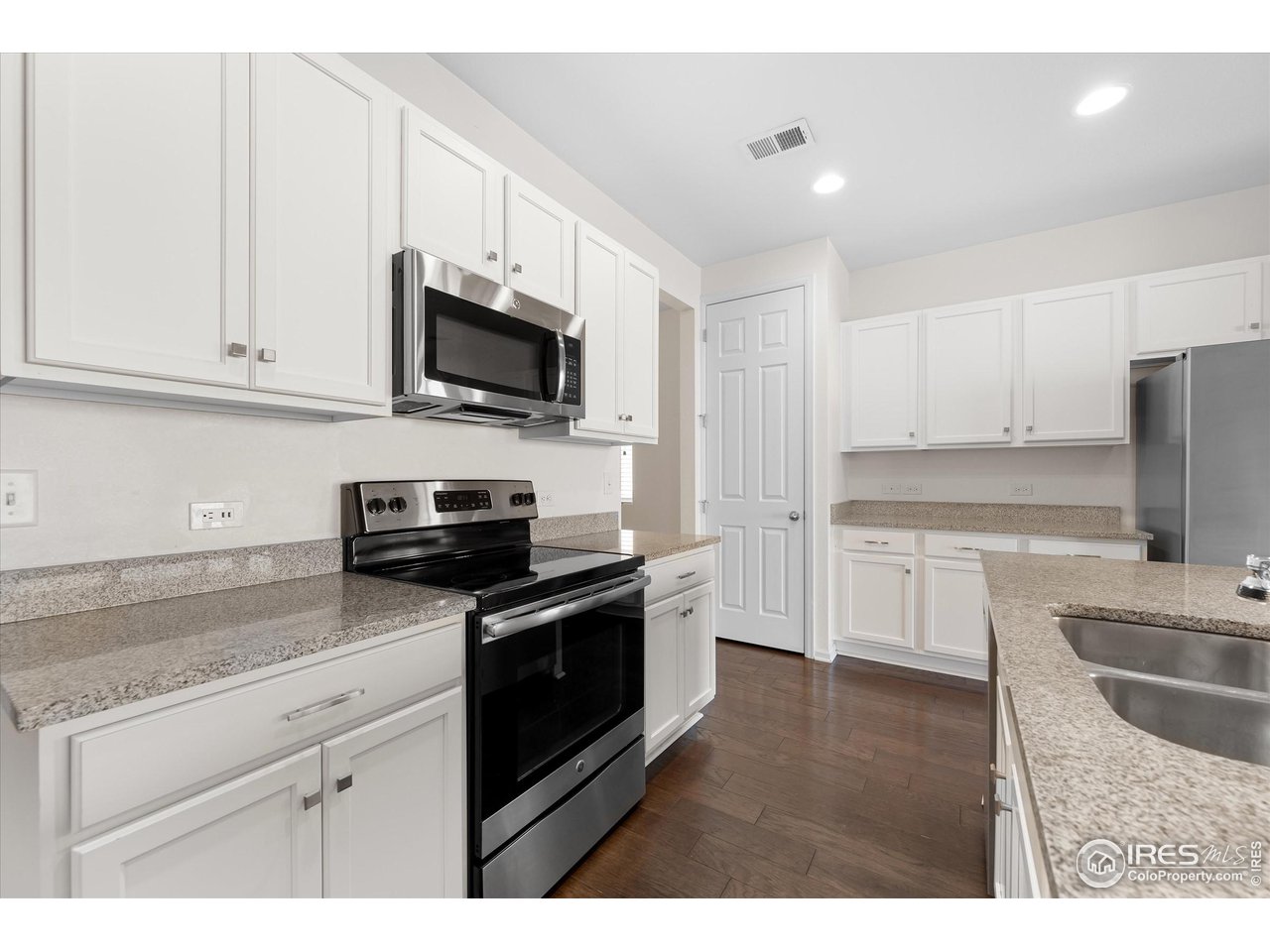 1604 Sorenson Drive Windsor, CO 80550 - Photo 8 of 32 a kitchen with granite countertop white cabinets and stainless steel appliances