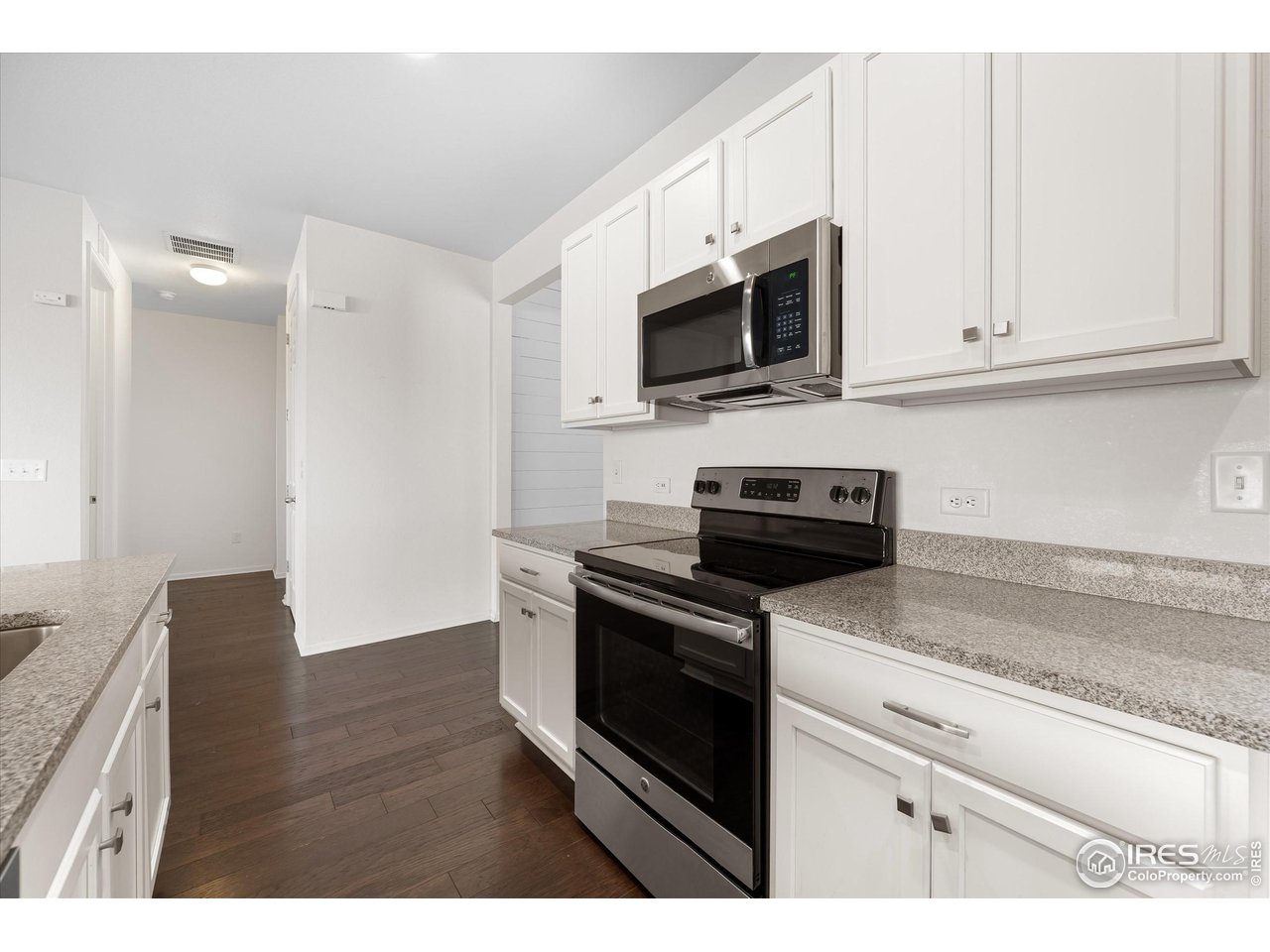 1604 Sorenson Drive Windsor, CO 80550 - Photo 10 of 32 a kitchen with stainless steel appliances granite countertop a sink a stove a microwave and wooden cabinets