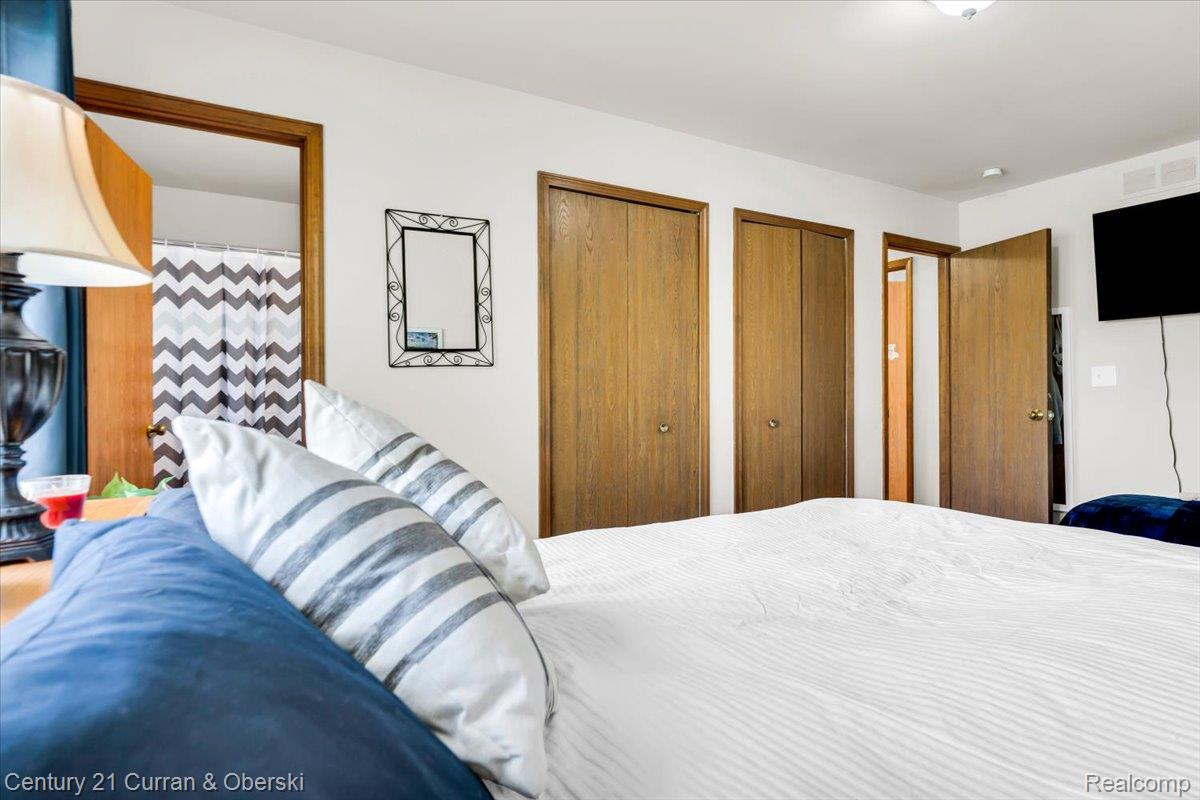 21439 Hall Road Trenton, MI 48183 - Photo 18 of 35 Bedroom featuring two wood-finish bifold closet doors, a wood-finish interior door, and a wall-mounted flat-screen television
