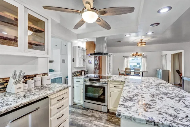 a kitchen with stainless steel appliances kitchen island granite countertop a stove and cabinets