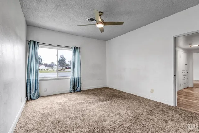 an empty room with chandelier fan and windows
