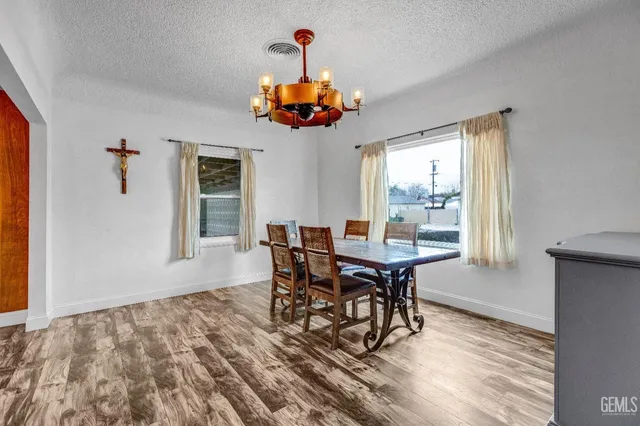 a dining room with wooden floor a chandelier a wooden table and chairs