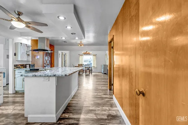 a view of a kitchen with kitchen island stainless steel appliances a sink and wooden floor