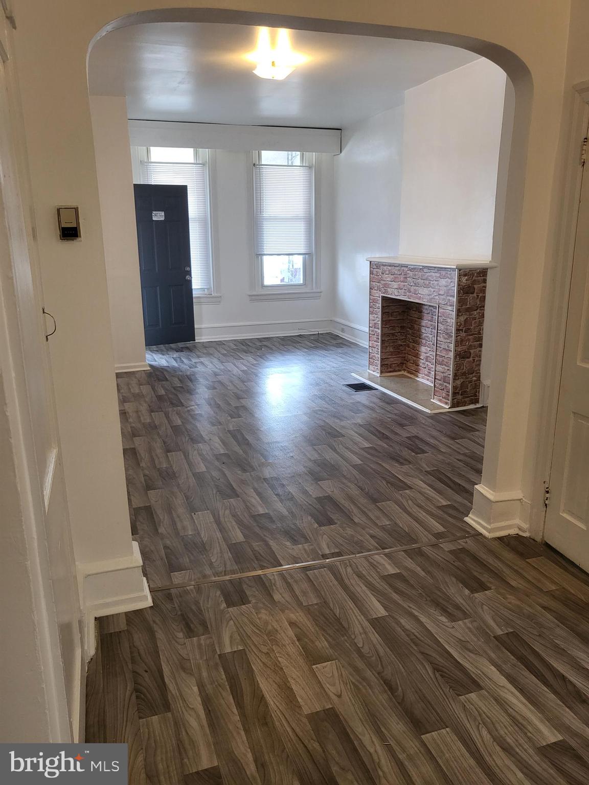 5820 Arch Street, Unit 1 Philadelphia, PA 19139 - Photo 5 of 9 a view of an empty room with wooden floor and a fireplace