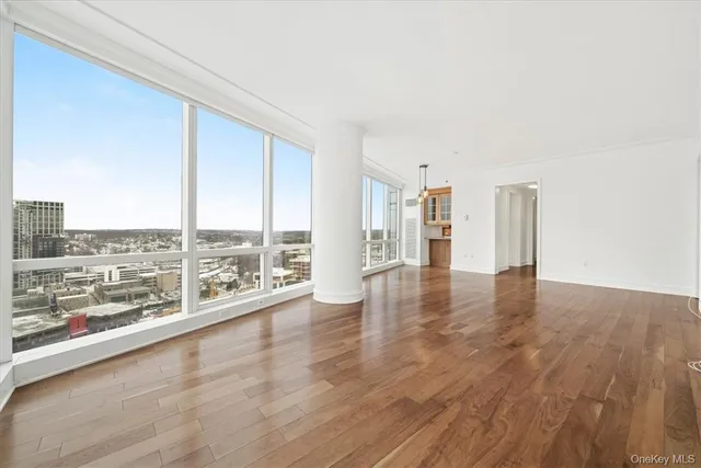 an empty room with wooden floor and large windows
