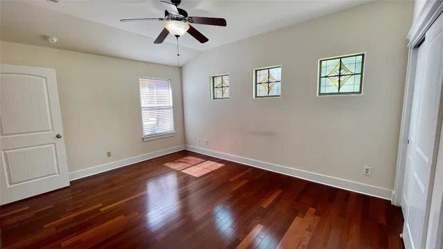 a view of an empty room with wooden floor and a window