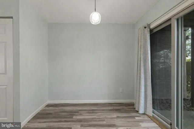 a view of an empty room with wooden floor and fan
