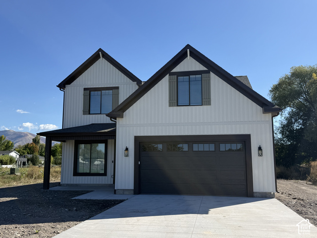 658 West 500 South, Unit 2 Logan, UT 84321 - Photo 1 of 18 Modern farmhouse exterior with white vertical siding, dark trim, a covered entry, an attached garage, and a concrete driveway