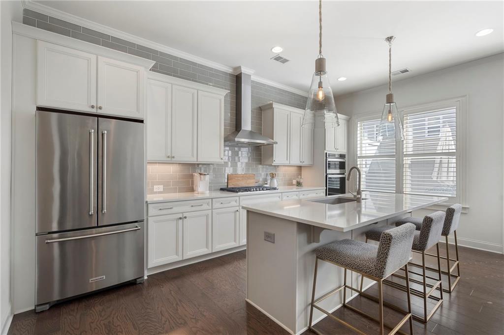 1076 Heyward Way Alpharetta, GA 30009 - Photo 10 of 57 a kitchen with stainless steel appliances granite countertop a refrigerator a sink dishwasher a stove and white cabinets with wooden floor