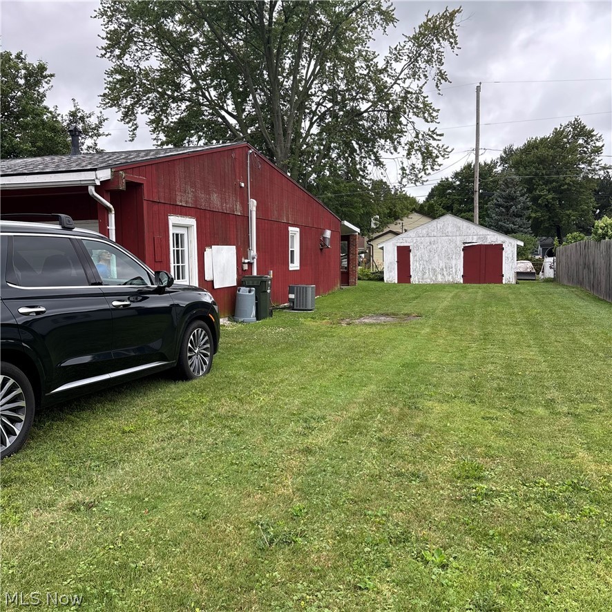 280 Erie Road Vermilion, OH 44089 - Photo 4 of 21 Expansive lawn area featuring a red exterior building with white trim, a detached white outbuilding with red doors, and a wood fence