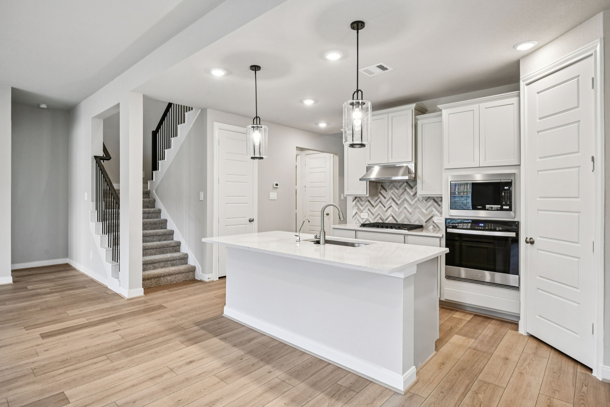 224 Raine Manor Montgomery, TX 77316 - Photo 15 of 50 a kitchen with stainless steel appliances kitchen island wooden floors wooden cabinets and white appliances