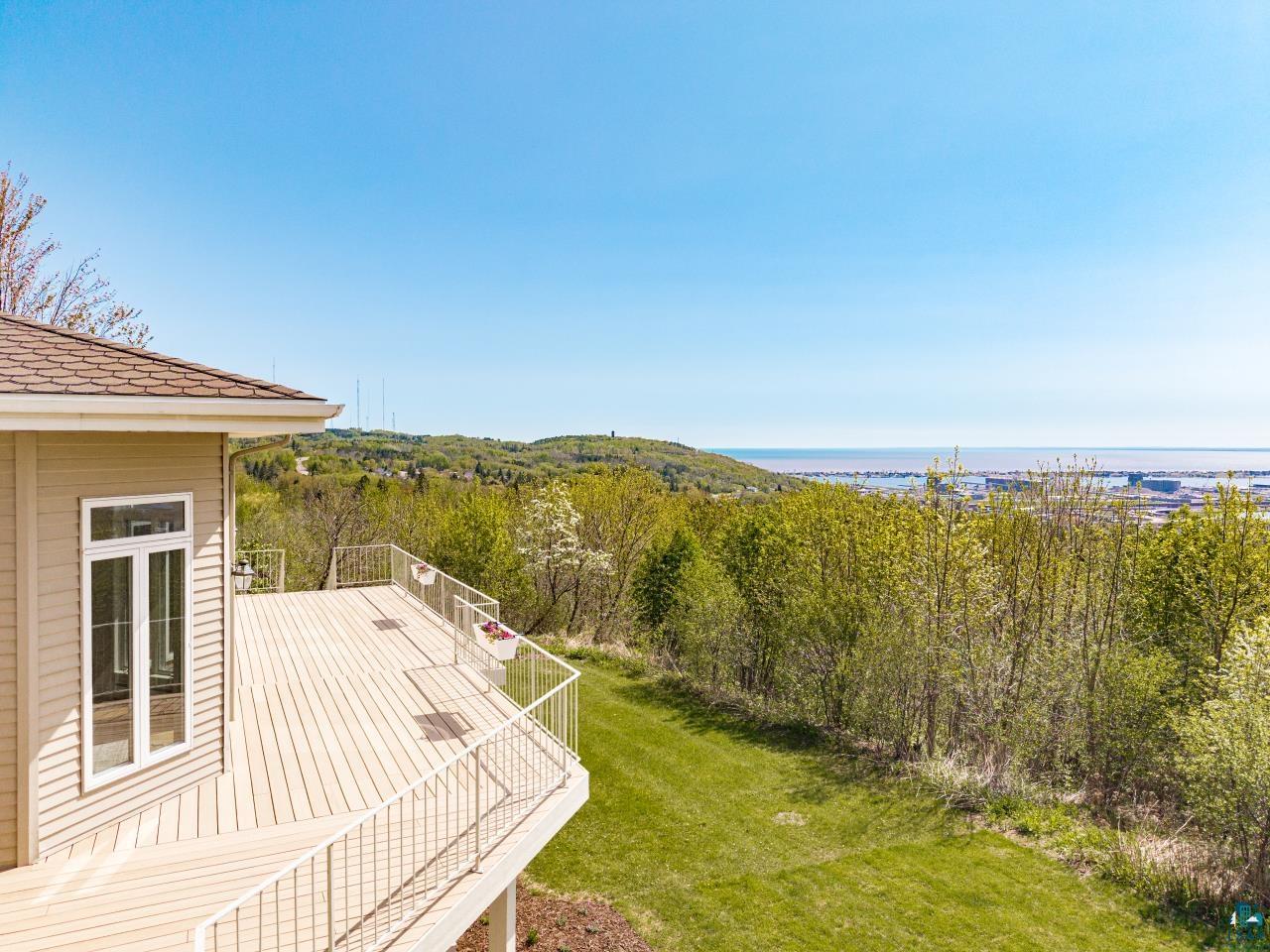 2906 West 15th Street Duluth, MN 55811 - Photo 8 of 98 Spacious outdoor deck featuring light-toned decking and white railing, ideal for enjoying expansive green landscapes and distant body of water