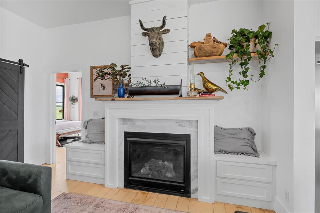 1197 Prairie Chapel Road Crawford, TX 76638 - Photo 11 of 40 Detailed view of wood finished floors, a barn door, a high end fireplace, and baseboards