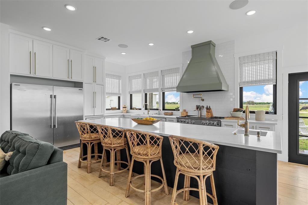 1197 Prairie Chapel Road Crawford, TX 76638 - Photo 12 of 40 Kitchen featuring wall chimney range hood, stainless steel appliances, a sink, light wood-style flooring, and recessed lighting