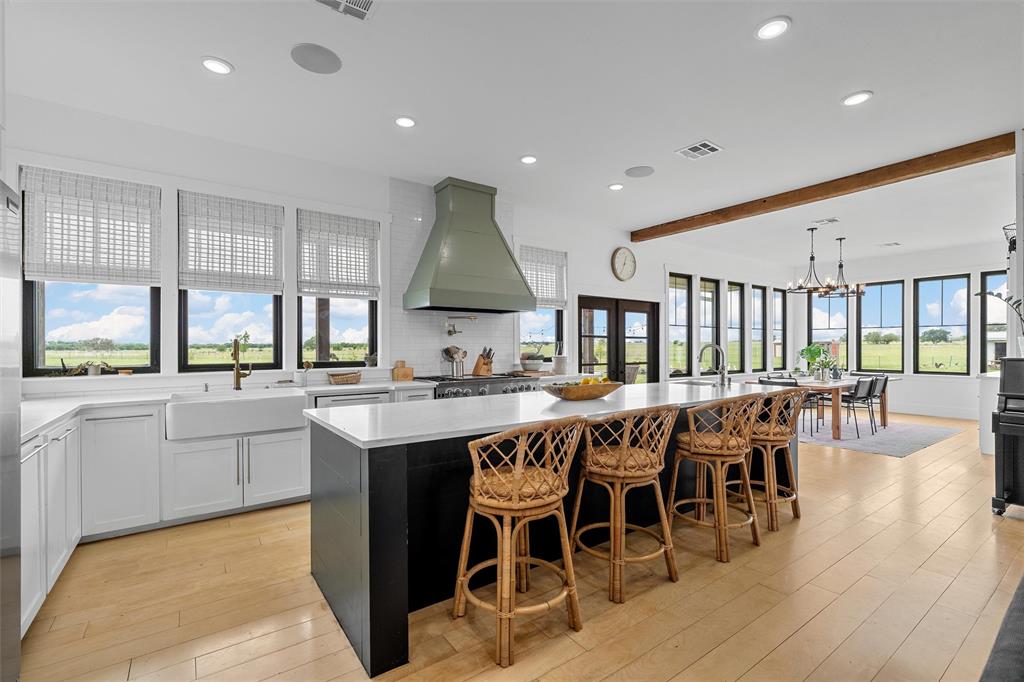 1197 Prairie Chapel Road Crawford, TX 76638 - Photo 15 of 40 Kitchen featuring a sink, wall chimney range hood, beamed ceiling, a spacious island, and light wood-style floors