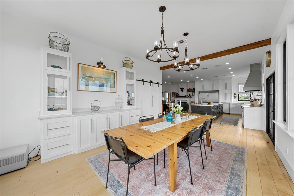 1197 Prairie Chapel Road Crawford, TX 76638 - Photo 17 of 40 Dining space with light wood-type flooring, a chandelier, a barn door, recessed lighting, and beamed ceiling