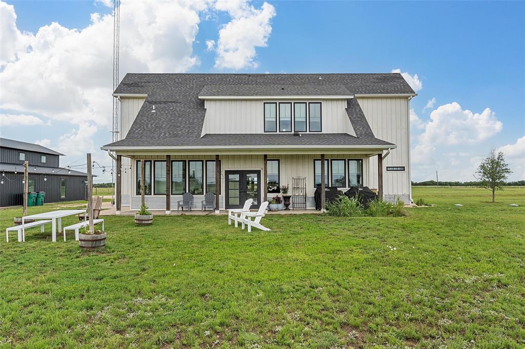 1197 Prairie Chapel Road Crawford, TX 76638 - Photo 32 of 40 Back of property featuring a lawn, a shingled roof, and a patio area